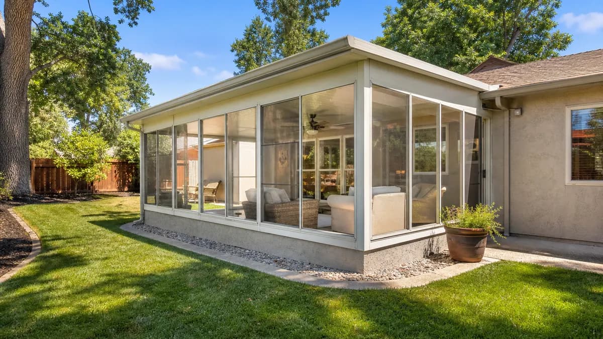 Glass sunroom addition with an insulated roof attached to a stucco home