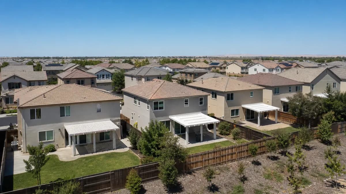 Elevated view over a newer two-story stucco subdivision in a flat valley with patio covers in the backyards